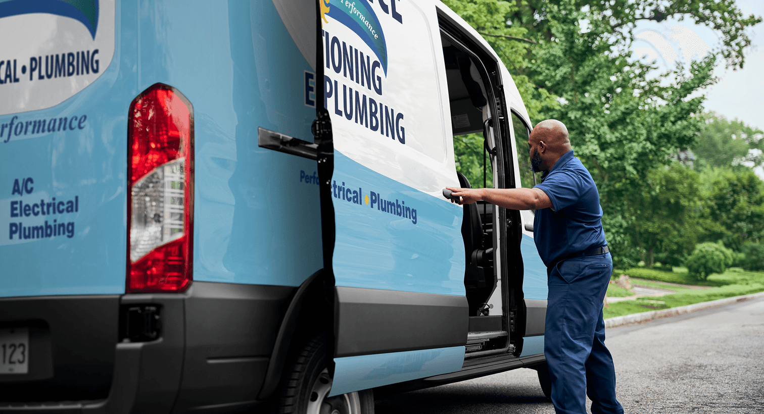 A professional Performance technician opening a service van on a residential street, ready to provide home HVAC, plumbing, and electrical services.
